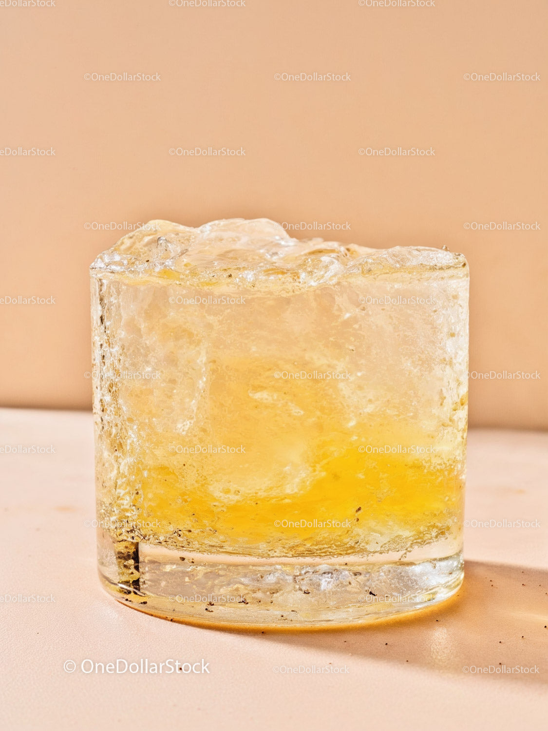 Close-up of translucent yellow ice cube on beige surface