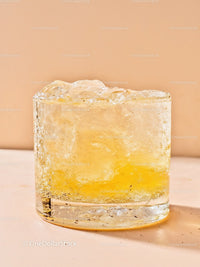 Close-up of translucent yellow ice cube on beige surface