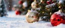 Golden and red Christmas baubles on snowy evergreen