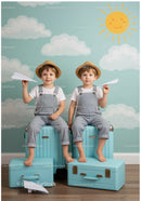 Twin boys playing with paper planes on blue suitcases