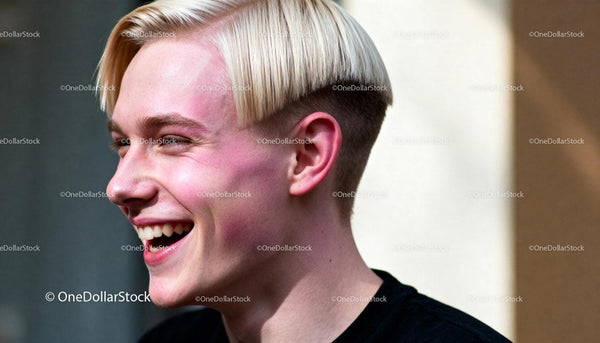 Młody mężczyzna śmiejący się z modną blond fryzurą typu miseczka