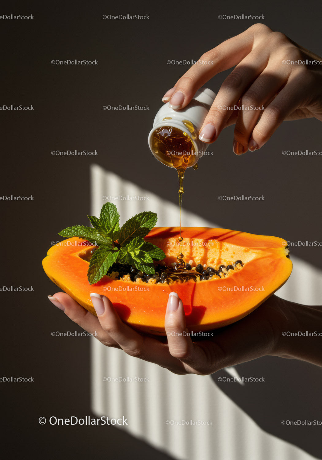 Pouring honey onto fresh papaya with mint leaves