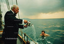 Elegant Man in Tuxedo Pouring Water on Young Man Swimming in Ocean