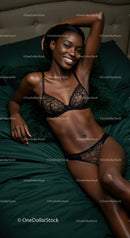 Smiling woman relaxing on dark green bed in lingerie