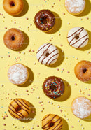 Assorted colorful donuts with sprinkles on yellow