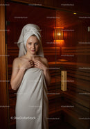 Young Woman Relaxing in Sauna with Towel and Hair Wrap