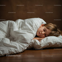 Peaceful child sleeping comfortably under white blanket