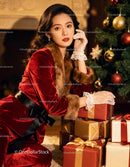 Elegant woman in festive red velvet dress with gifts