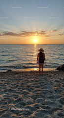 Woman enjoying peaceful sunset at calm sandy beach