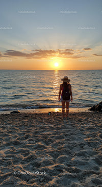 Woman enjoying peaceful sunset at calm sandy beach