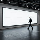 Man Walking Past Large Illuminated Blank Billboard Indoors