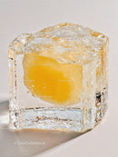 Yellow fruit frozen inside a clear ice cube closeup