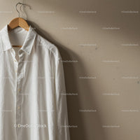 Classic white shirt hanging on wooden hanger indoors
