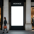 Woman walking past blank illuminated city billboard