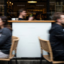 People Passing by Outdoor Café with Coffee Cups