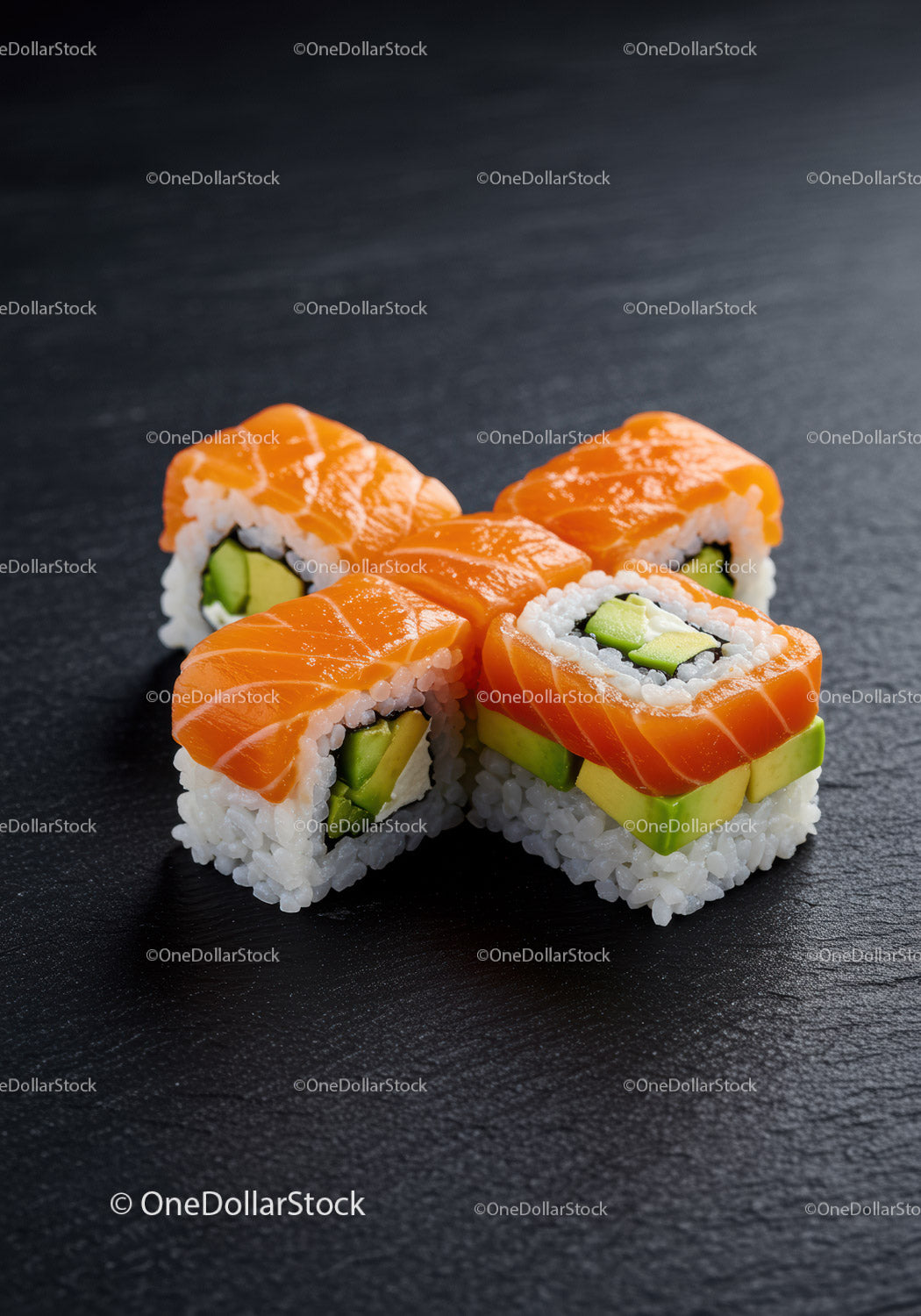 Fresh salmon sushi rolls with avocado on black slate