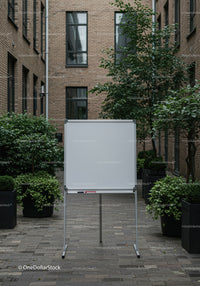 Blank whiteboard in modern urban courtyard with greenery