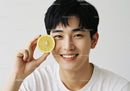 Smiling Young Man with Lemon Slice in Bright Indoor Setting