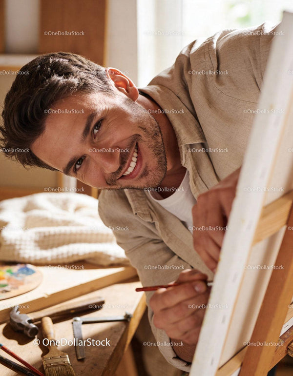 Smiling man focused while painting on canvas indoors