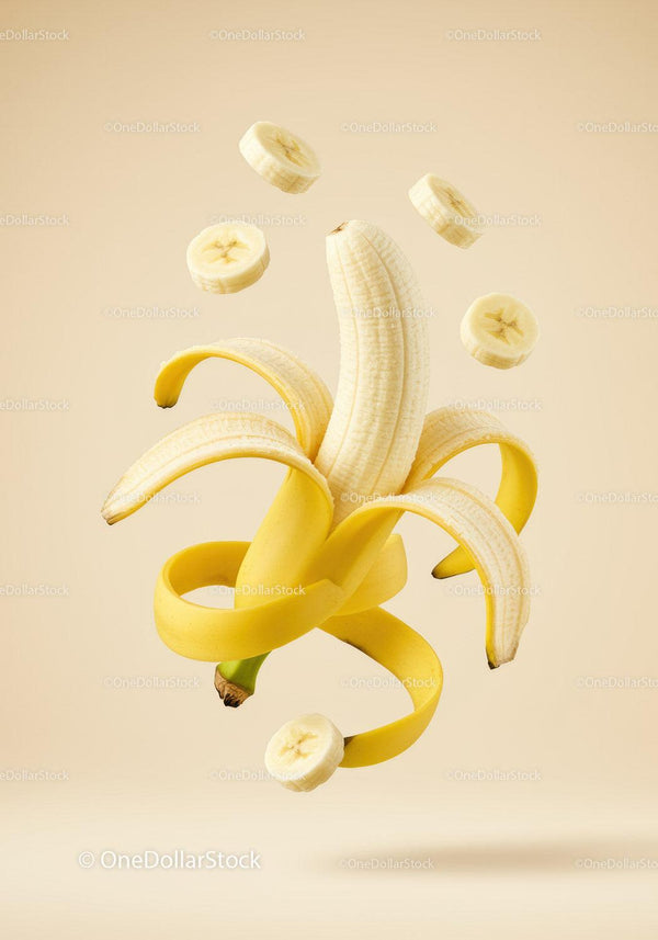 Peeled banana with floating banana slices on beige background