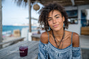 Young Woman Relaxing at Beachside Cafe with Ocean View