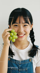 Young Girl Smiling Cheerfully While Holding Green Grapes