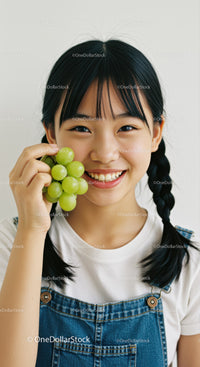 Young Girl Smiling Cheerfully While Holding Green Grapes