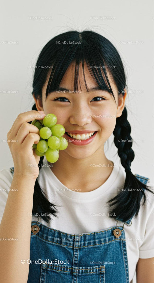 Young Girl Smiling Cheerfully While Holding Green Grapes