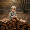 Young boy sitting on firewood stack holding red apple
