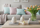 Spring tulip bouquet and pastel cushions on gray sofa