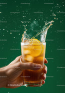 Refreshing iced lemon tea splash in hand on green background