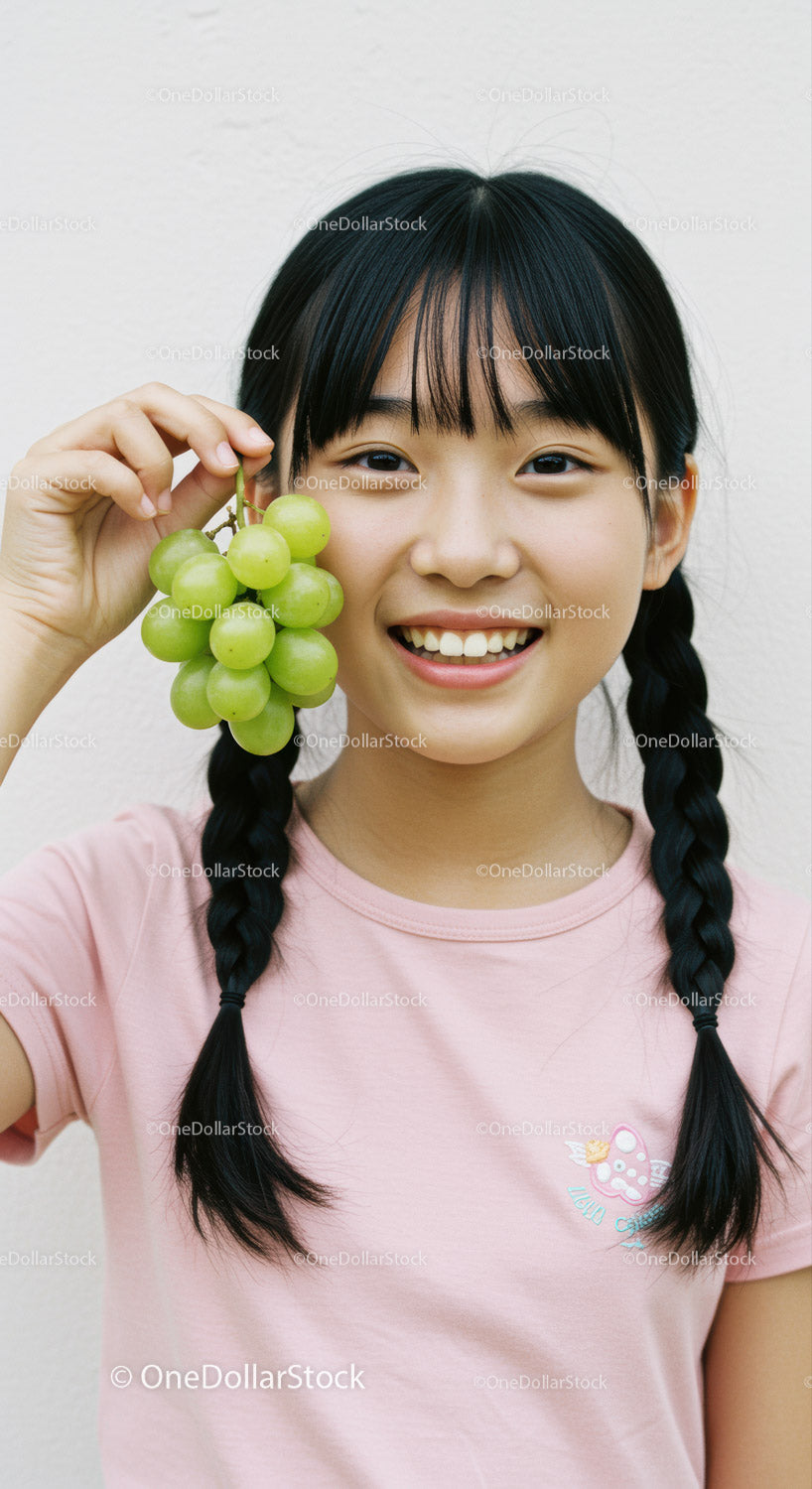 Young Girl Smiling with Green Grapes in Bright Casual Setting