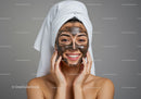 Young woman with facial clay mask and towel on head