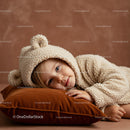 Toddler in Cozy Bear Onesie Resting on Velvet Pillow