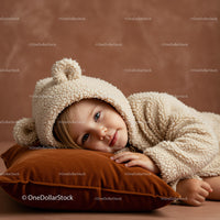 Toddler in Cozy Bear Onesie Resting on Velvet Pillow