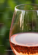 Close up of rosé wine glass with blurred green background