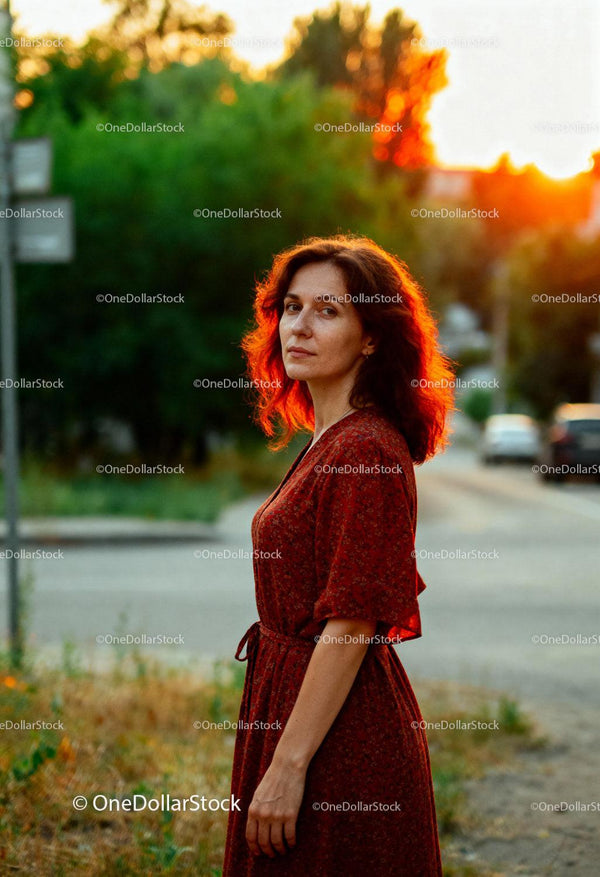 Woman in Red Dress Standing by the Road at Sunset