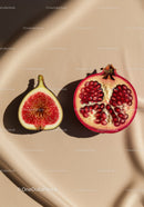 Fresh fig and pomegranate halves on beige fabric