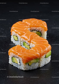 Fresh salmon avocado sushi rolls on black slate