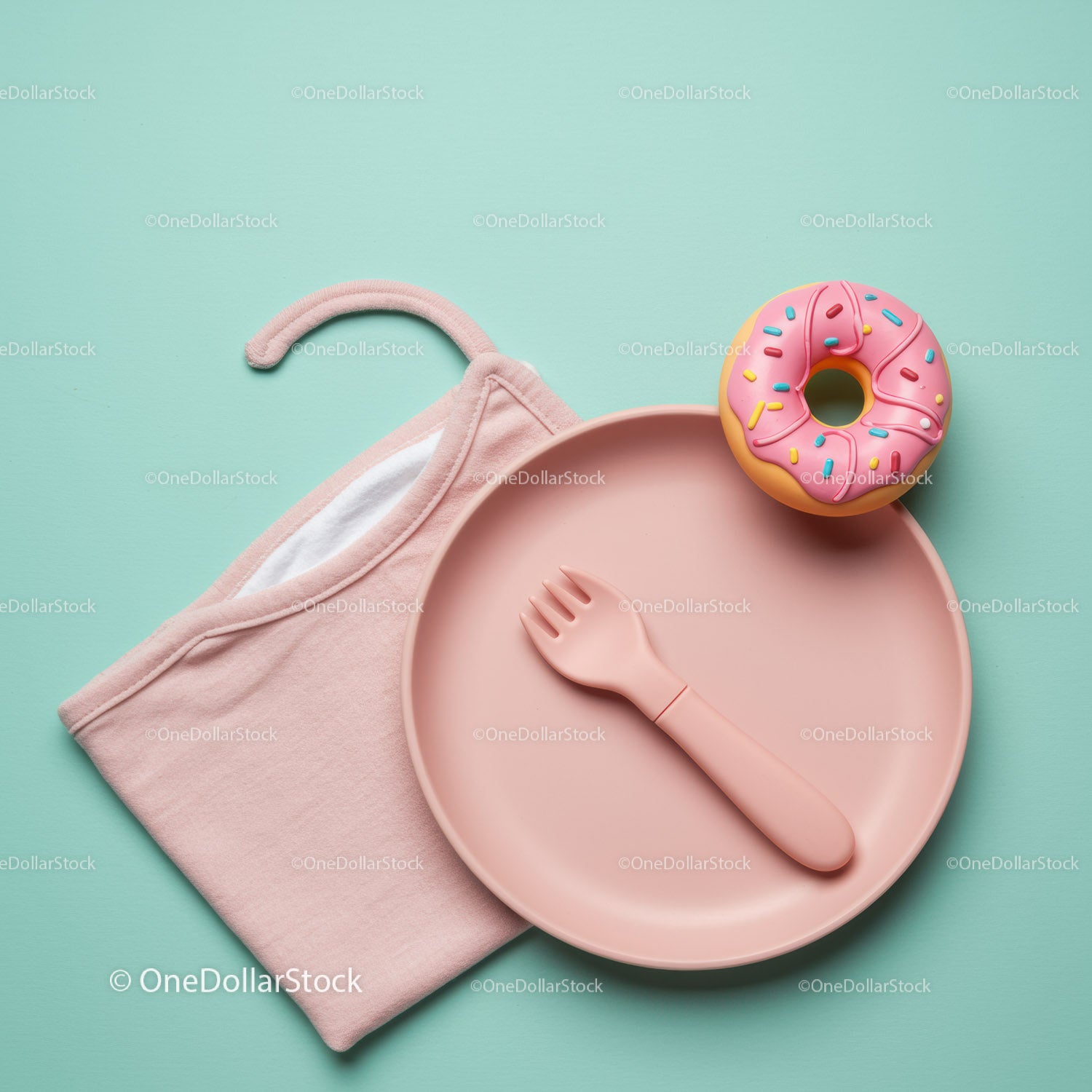 Pink baby plate with spork and toy donut on blue background