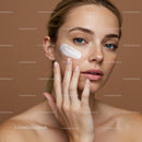 Close-Up of a Woman Applying Cream to Her Face with Freckles Under Natural Light