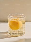 Clear glass with floating peach in sparkling water