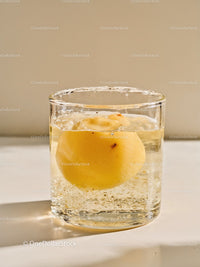 Clear glass with floating peach in sparkling water