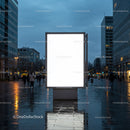 Empty illuminated billboard on rainy city street at dusk
