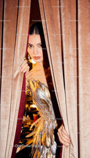 Elegant woman in feathered dress peeks through velvet curtain
