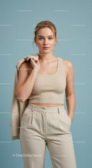 Chic Young Woman in Beige Crop Top and Trousers Standing Against Blue Background