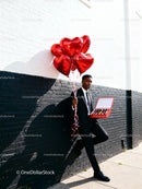 Man in Suit Holding Heart Balloons and Chocolates Outdoors