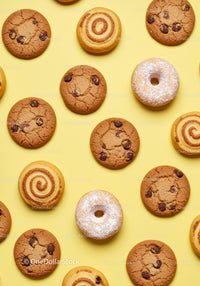 Assorted cookies and powdered donuts on yellow background