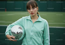 Young Woman in Mint Green Sports Jacket Holding Disco Ball on Tennis Court