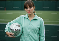 Young Woman in Mint Green Sports Jacket Holding Disco Ball on Tennis Court